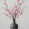 Ramitas de flor de ciruela blanca artificiales en rosa y blanco en un jarrón gris oscuro