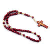 A wooden rosary beads necklace featuring a string of red beads and a small wooden Jesus crucifix.