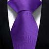 A purple silk necktie tied in a knot against a black suit jacket and white shirt.