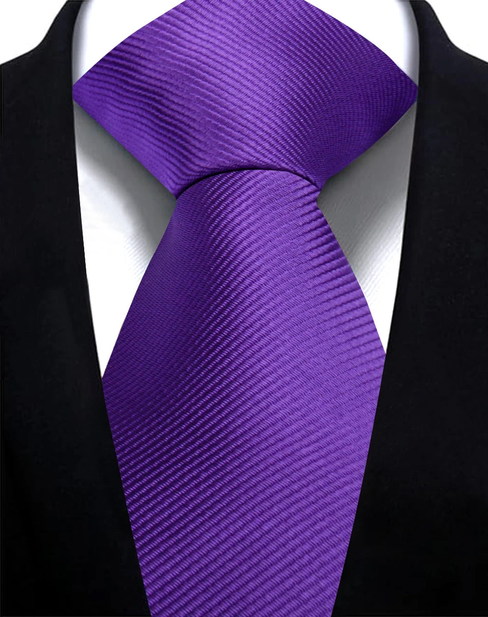 A purple silk necktie tied in a knot against a black suit jacket and white shirt.