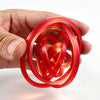 A hand holds a bright red rotating ball spinner fidget toy with intricate interwoven rings.