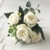 A bouquet of white silk roses and peonies with dark green foliage for home and event decor.