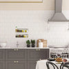 A kitchen setup featuring a clear acrylic floating storage rack set mounted on a white subway tile backsplash.