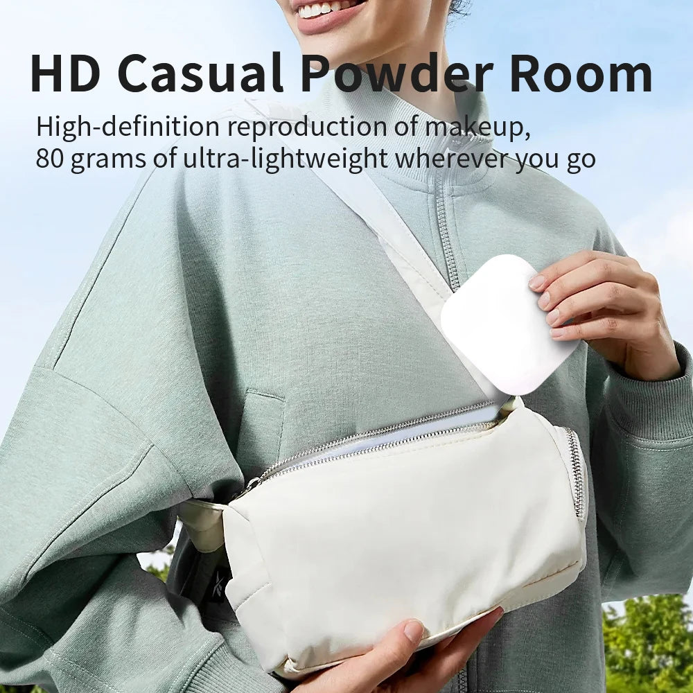 A person holds a white compact powder room mirror in their hand against a light green jacket.