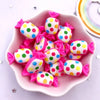 A pink bowl filled with colorful candy resin cabochons in various polka dot patterns for crafting.