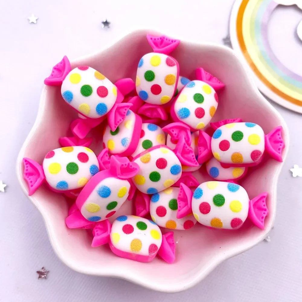 A pink bowl filled with colorful candy resin cabochons in various polka dot patterns for crafting.