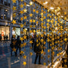 A vertical display of shimmering metallic gold star garlands hanging in a storefront window.