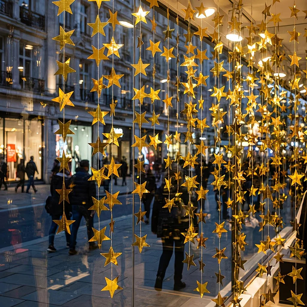 A vertical display of shimmering gold star garlands hanging in a storefront window.