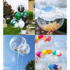 A hand holds a large clear bubble balloon reflecting the sky and clouds, with other balloons visible in the background.