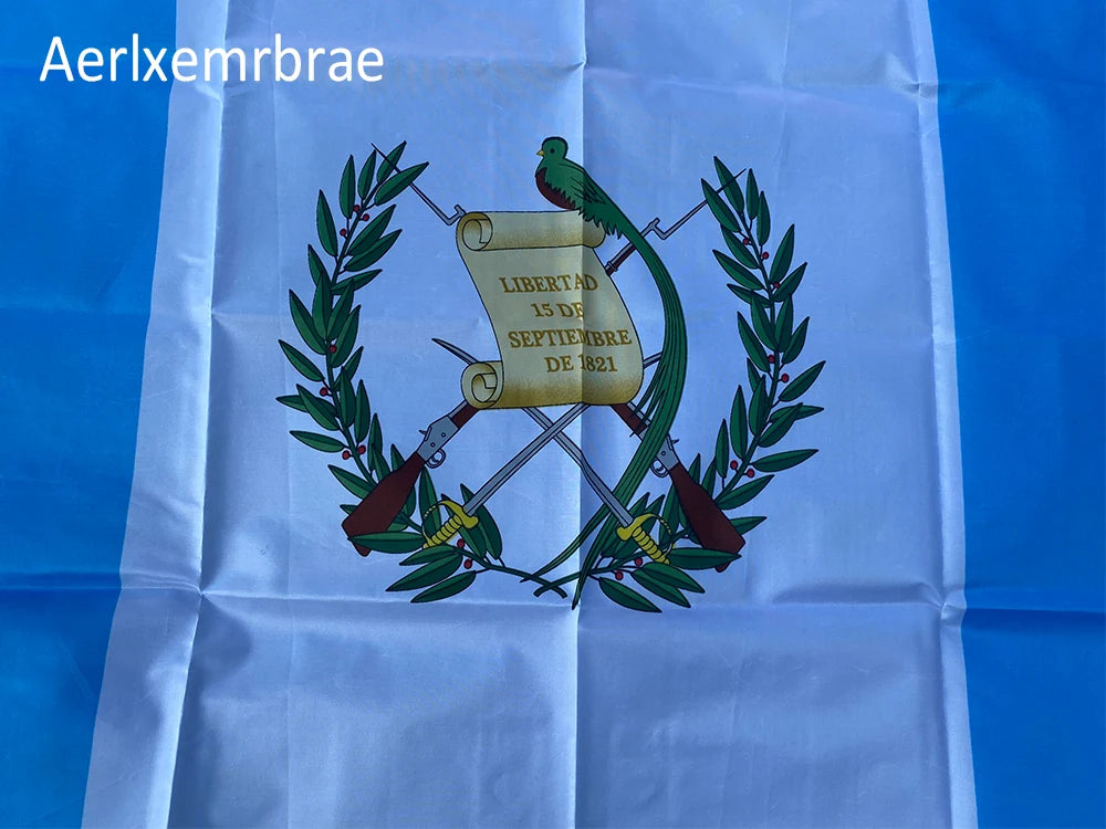 Guatemala National Flag displayed on white fabric with a green laurel wreath and text.