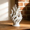 White modern plastic flower vase with organic, flowing lines sitting on a wooden surface.