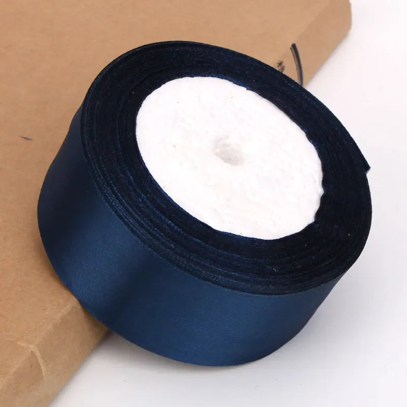 Roll of dark blue satin ribbon for crafts and gift wrapping placed on brown paper.
