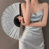 A woman holds a silver glitter holographic hand fan against a gray background.