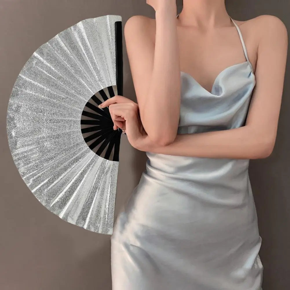 A woman holds a silver glitter holographic hand fan against a gray background.