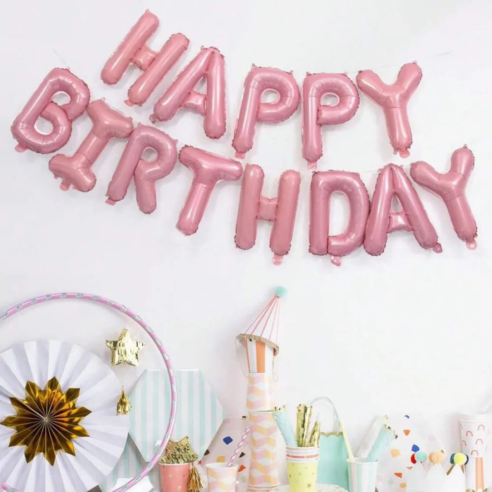 A display of pink foil letter balloons spelling out Happy Birthday against a white background.