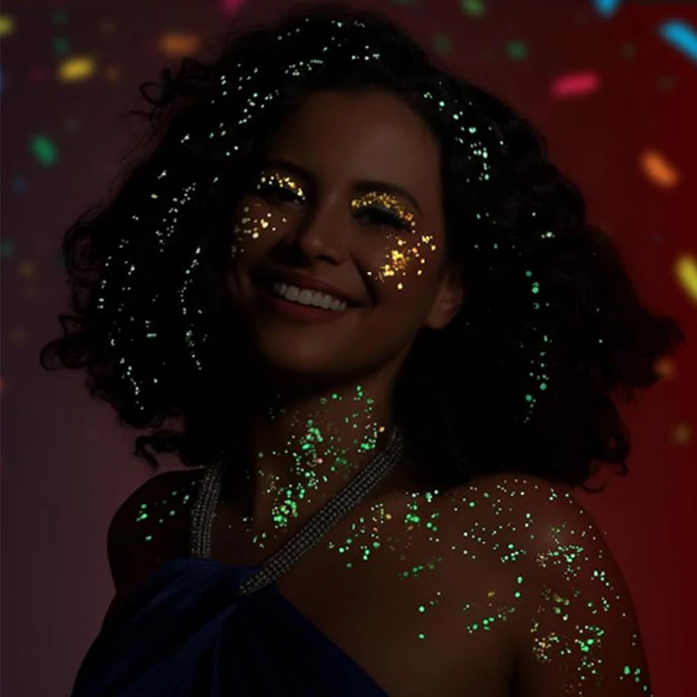 A woman with dark curly hair is covered in glowing green glitter on her face and shoulders.