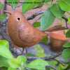 A brown metal bird sculpture perched on a branch amidst green leaves for garden decor.