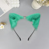 A pair of bright teal plush fox ears headband with black straps displayed on a gray surface.