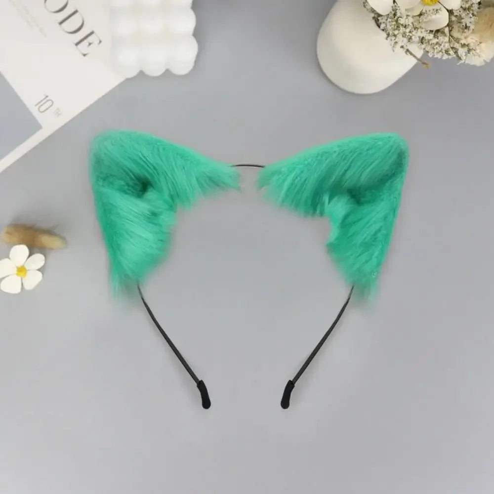 A pair of bright teal plush fox ears headband with black straps displayed on a gray surface.