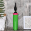 A bright green handheld balloon air pump with a black nozzle is shown against a rustic wooden background.