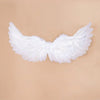 White angel feather wings costume prop with adjustable straps against a beige background