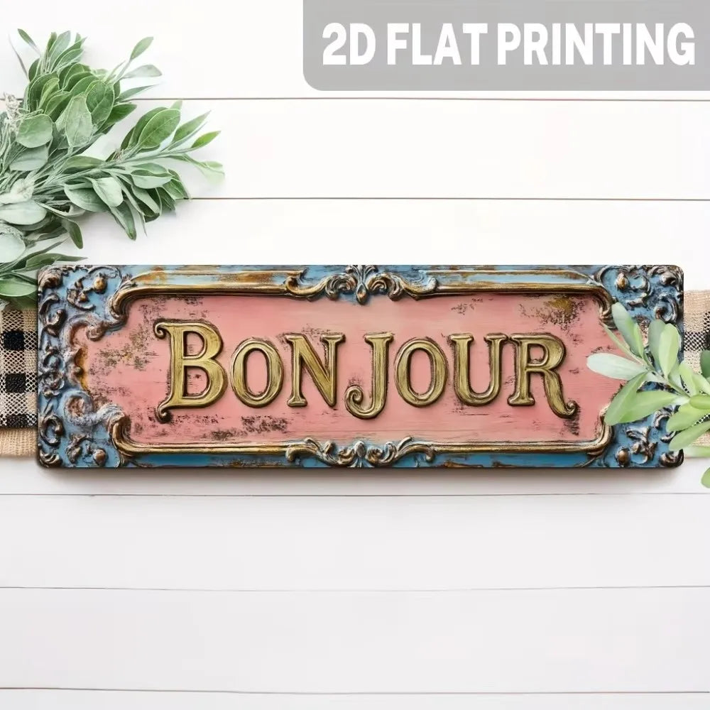 A vintage metal sign with the word BONJOUR painted in gold on a distressed pink background, set against a white wooden surfac