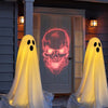 Two white ghost decorations with glowing faces are displayed in front of a white door.