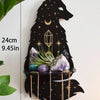 A black silhouette of a wolf head with stars, holding crystals, and a crescent moon, mounted on a floating shelf.