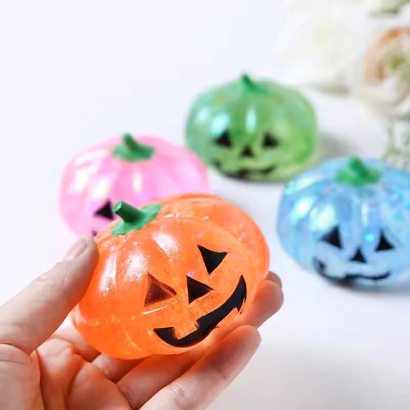 An orange Halloween pumpkin stress ball is held in a hand, surrounded by other green and pink pumpkins.
