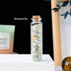A glass bottle filled with Amazonite crystals sitting on a white surface.