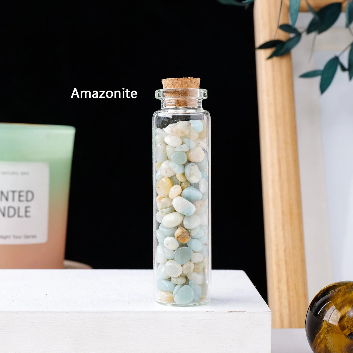 A glass bottle filled with Amazonite crystals sitting on a white surface.