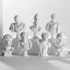 A collection of plaster bust miniatures depicting figures from Greek mythology, displayed against a white background.