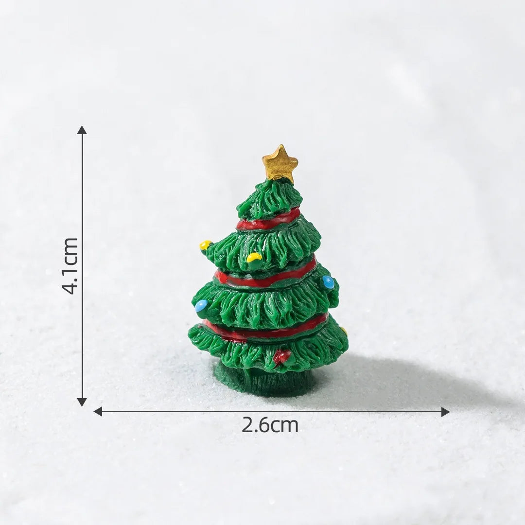 A small, green resin Christmas tree charm with a gold star topper resting on a white surface.
