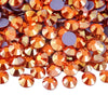A close-up view of mixed size crystal and glass rhinestones in shades of orange, gold, and purple.