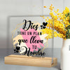 A clear acrylic sign featuring a religious quote and decorative elements on a wooden base.