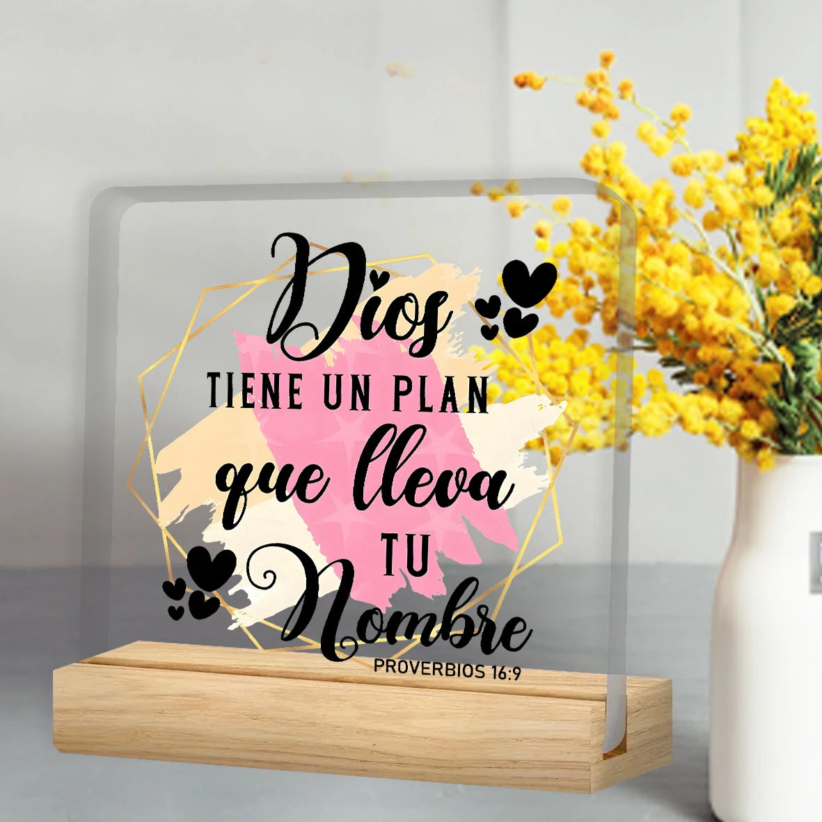 A clear acrylic sign featuring a religious quote and decorative elements on a wooden base.