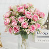 A bouquet of pink and blush roses with green foliage arranged in a clear glass vase.