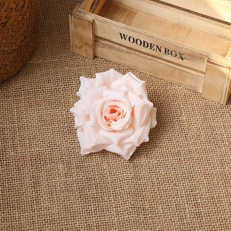 A delicate pink rose flower rests on burlap next to a wooden box labeled WOODEN BOX.
