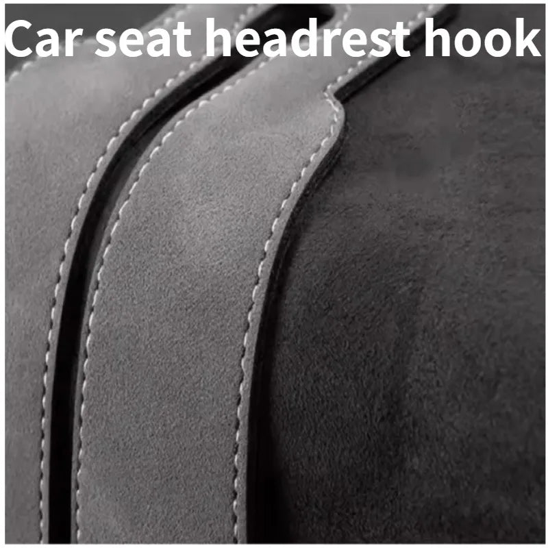 Close-up of a car seat headrest hook, showing the leather strap and stitching.
