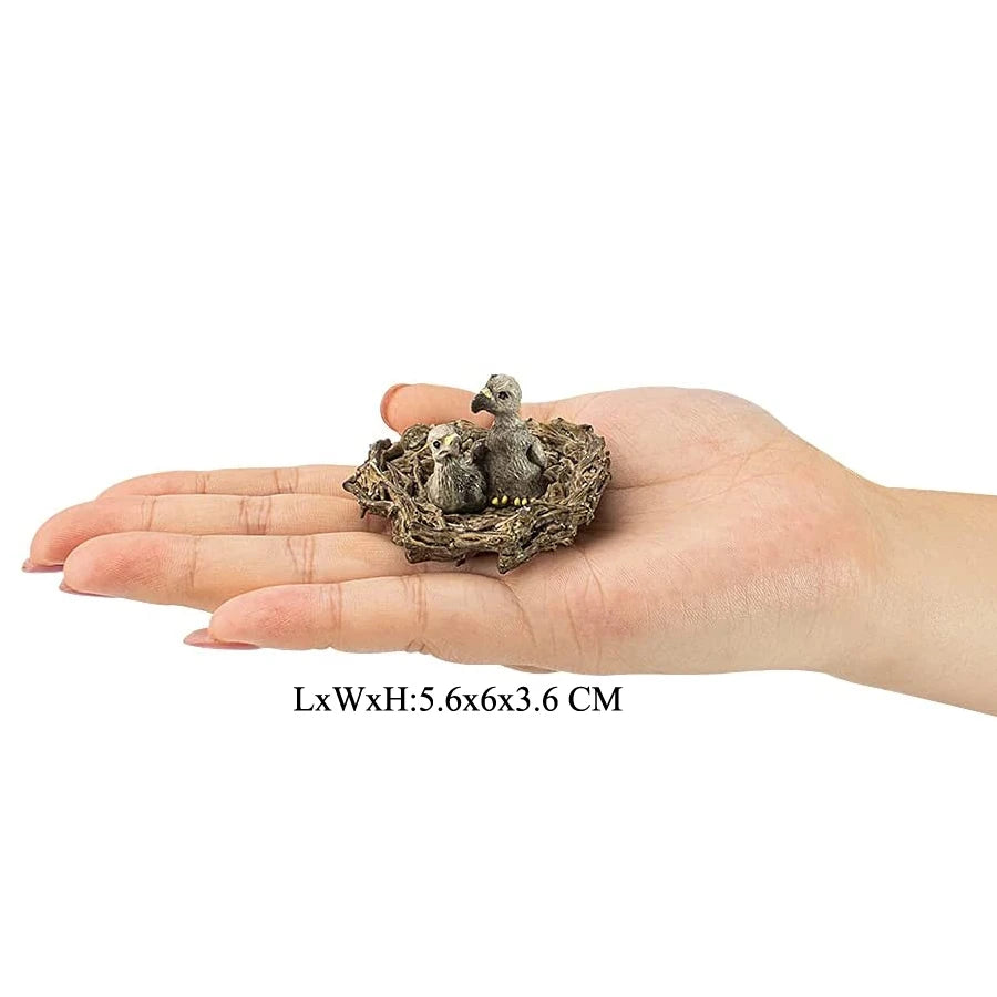 A hand holds a figurine set of realistic birds of prey, including an owl, vulture, and bald eagle, nestled in a natural nest.