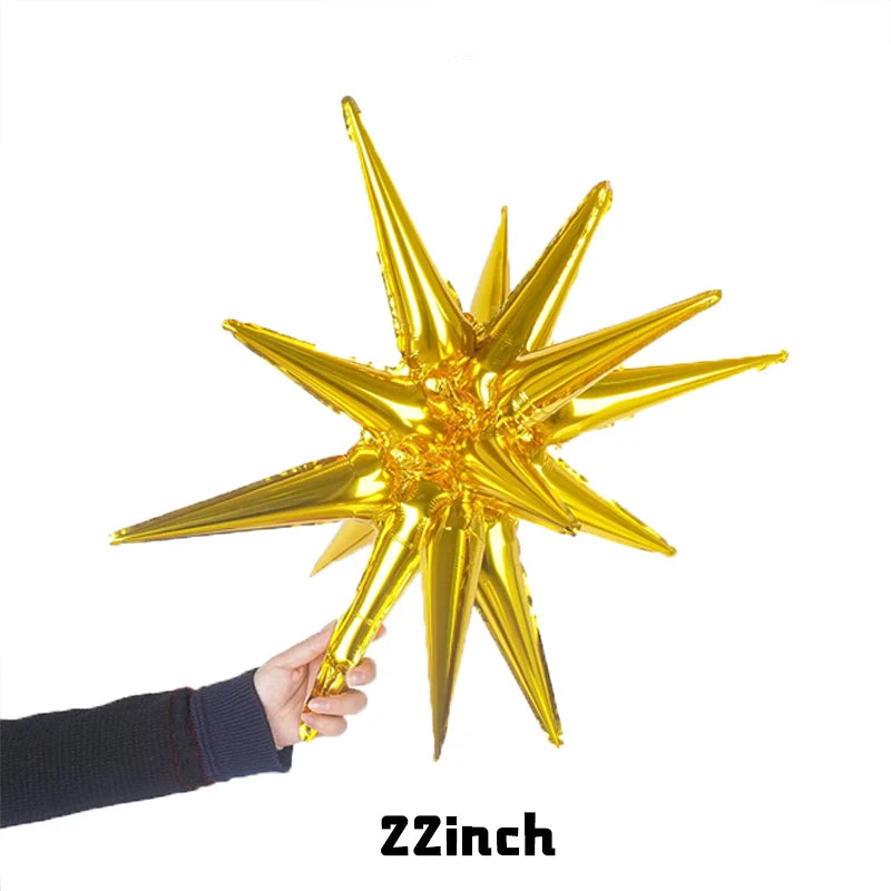 A hand is holding a gold star burst foil balloon against a white background.