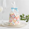 A clear plastic bag filled with colorful pastel satin ribbon bows on a white plate.
