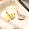 Gold and silver openable book pendant necklace with an engraved message on a white background.