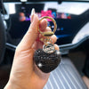 A hand holds a gold-colored keychain featuring a heart-shaped black crystal charm.