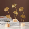 A set of three golden ginkgo leaf metal decorative sculptures displayed on wooden bases.