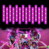 A group of people celebrating with pink LED foam glow sticks illuminating the background.
