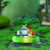 A green tree ornament featuring a small gray animal figurine on a mossy base.