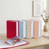 A set of elegant gold foil heart photo albums in various pastel colors, displayed on a wooden table.