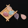 A collection of polished agate and rose quartz gemstone pendants displayed on a wooden tray.