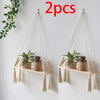 Two macrame wood floating wall shelves with hanging rope displaying potted plants.